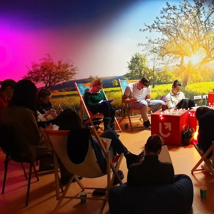 grupa osób siedząca na leżakach w przyciemnionej sali szkoleniowej