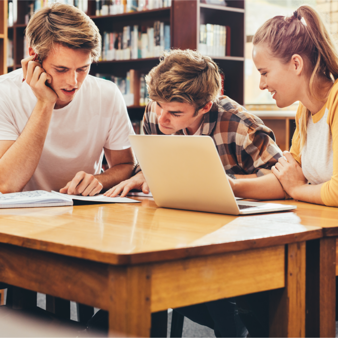 Grupa trzech studentów siedząca przy biurku