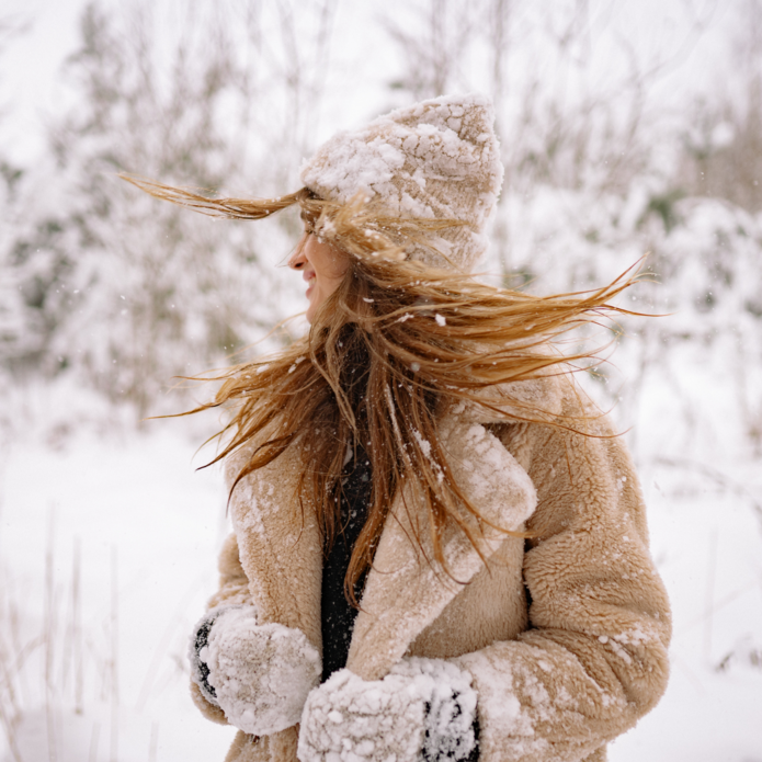 uśmiechnięta kobieta w zaśnieżonym płaszczu